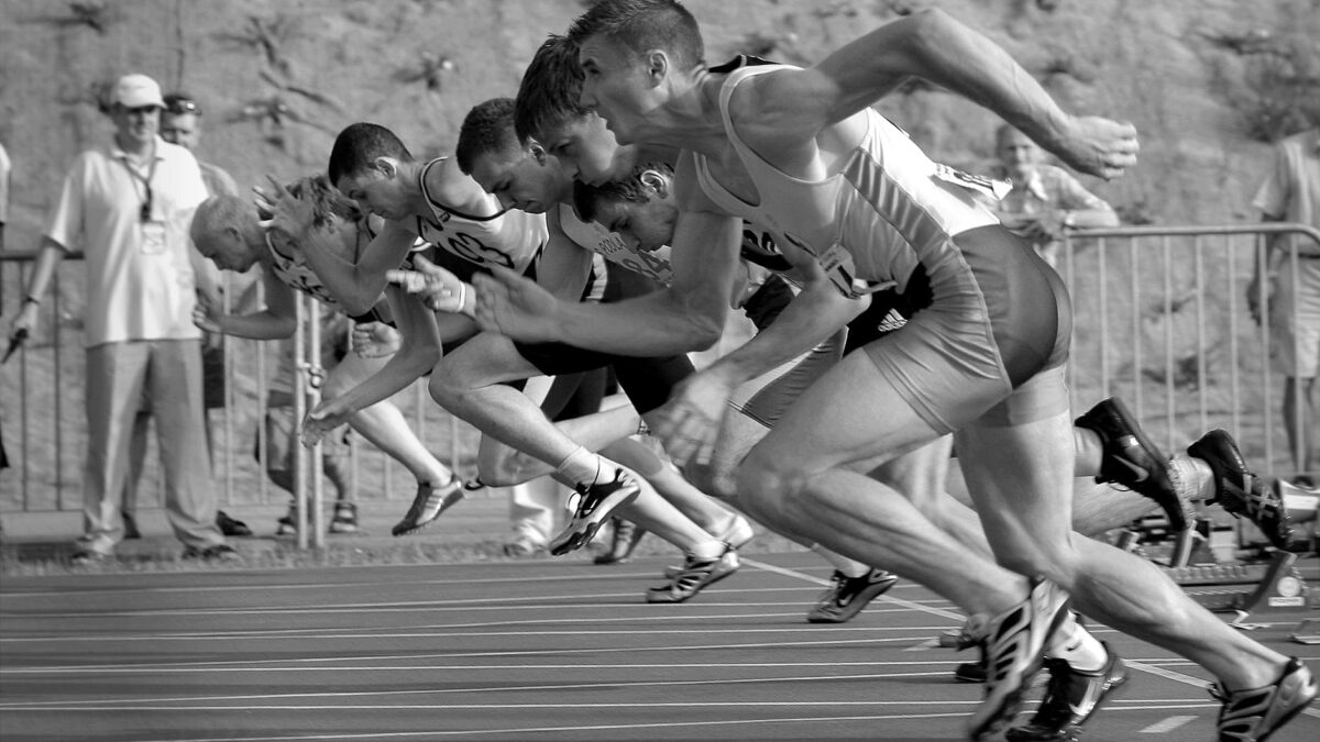 athletes running on track and field oval in grayscale photography