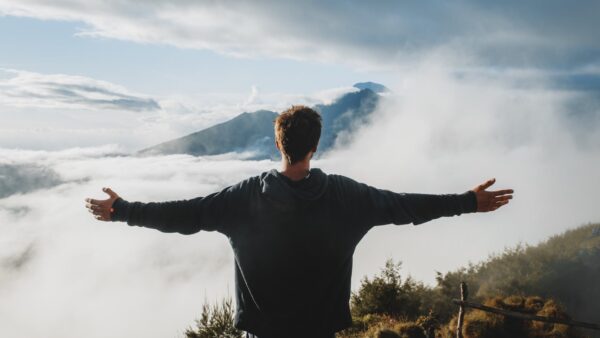 man with arms outstretched admiring view from mountain cliff