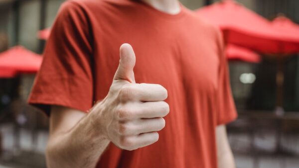 unrecognizable man showing thumb up on city street