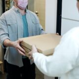 man wearing a face mask receiving a pizza delivery