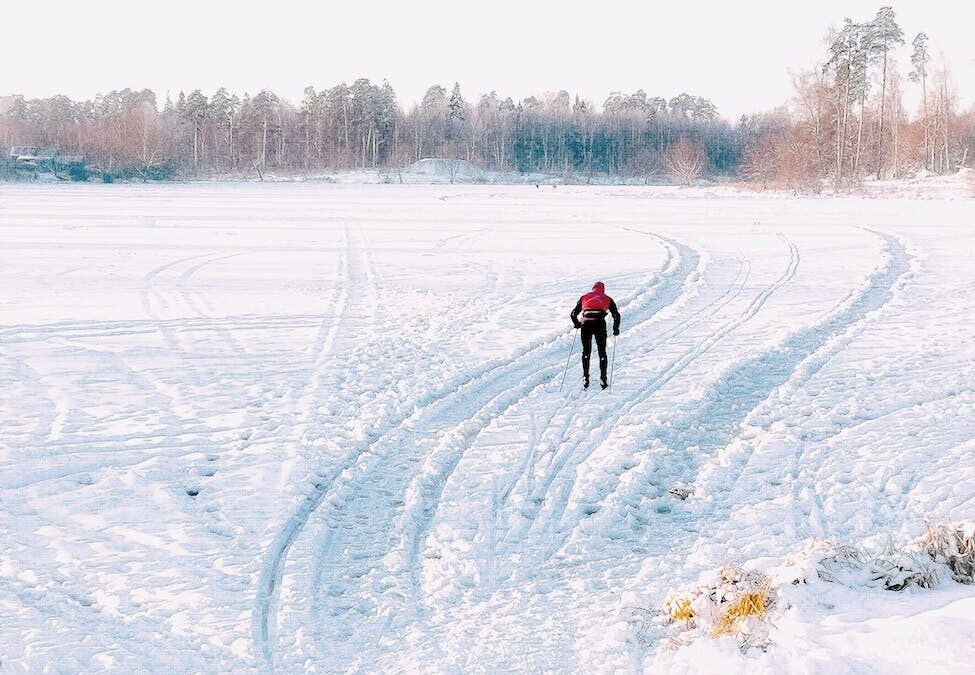 person in red jacket and blue pants walking on snow covered ground