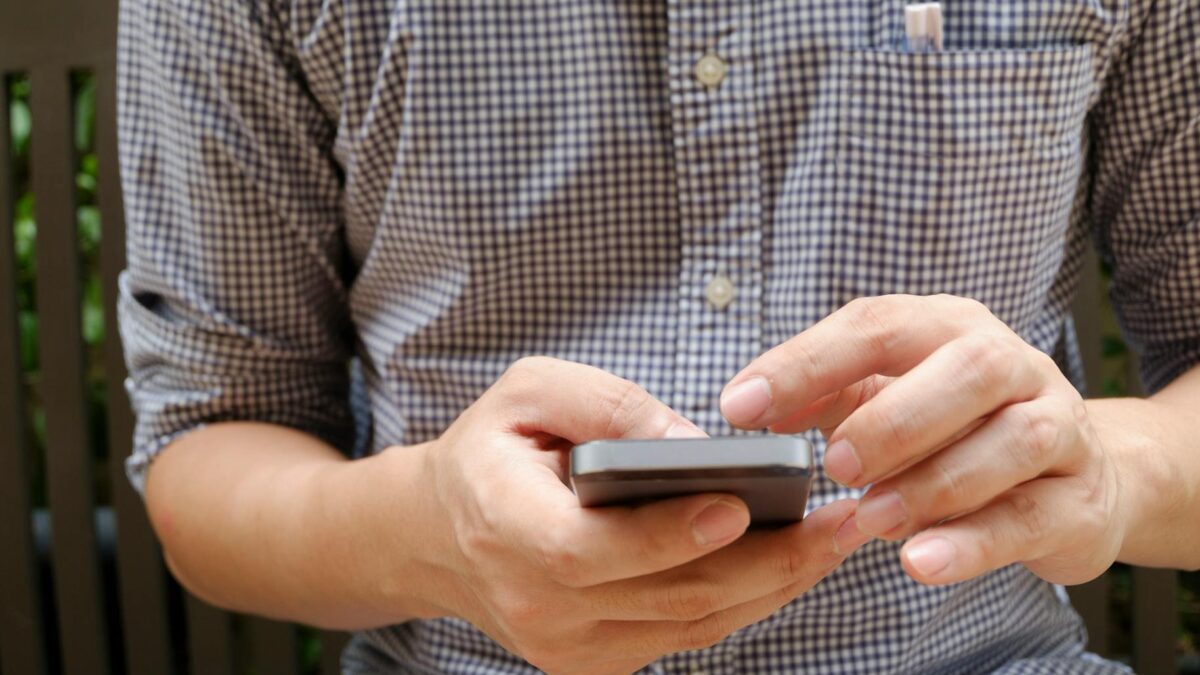 man in plaid shirt using smartphone