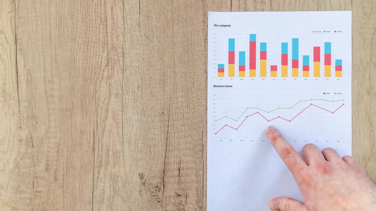 person pointing paper line graph