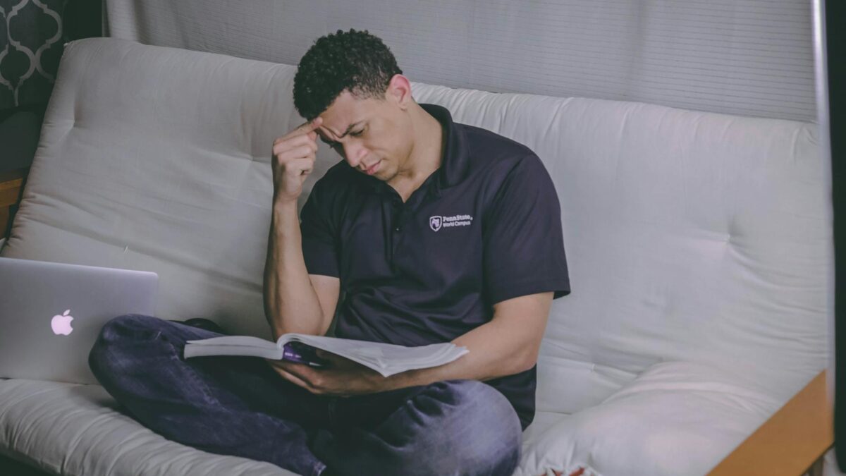 man sitting on sofa reading book