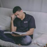 man sitting on sofa reading book