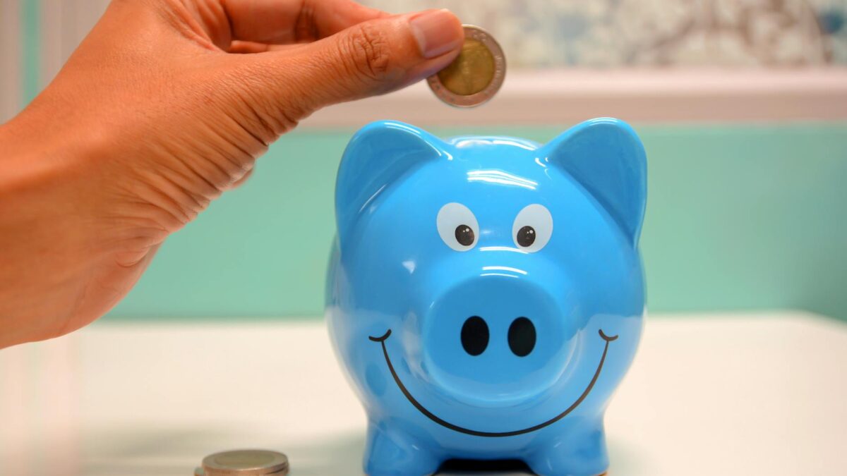 person putting coin in a piggy bank