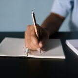 close up shot of a person writing on a notebook