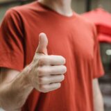 unrecognizable man showing thumb up on city street