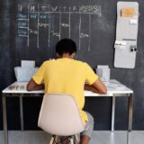 boy in yellow crew neck t shirt sitting on chair