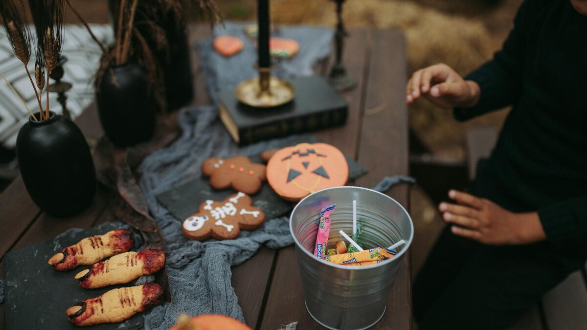 a person sitting at a table with halloween decorations and a bucket of candies