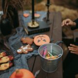 a person sitting at a table with halloween decorations and a bucket of candies