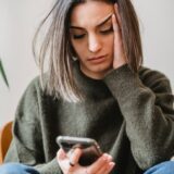 concerned woman browsing smartphone in room