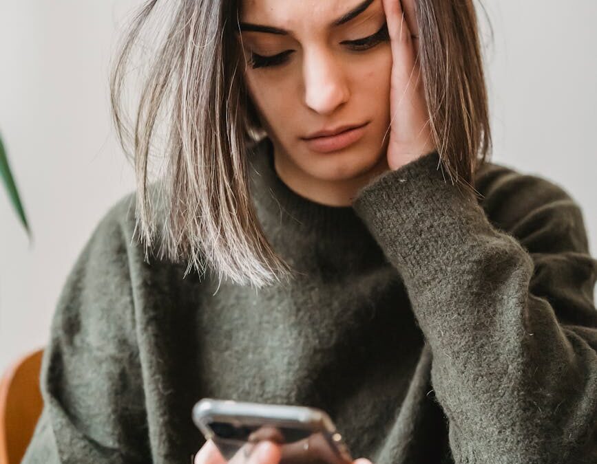 concerned woman browsing smartphone in room