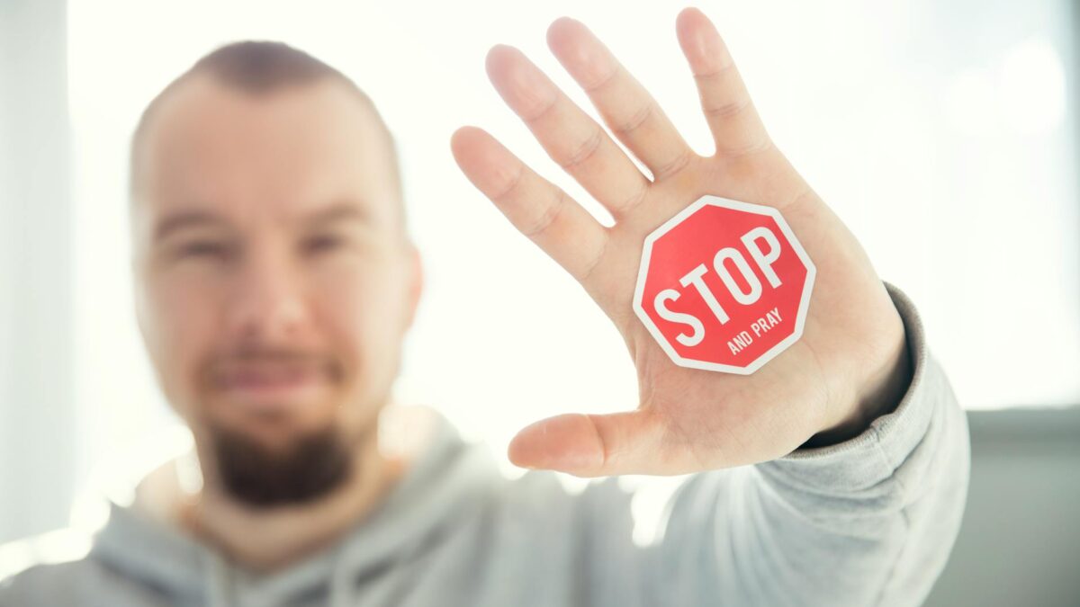 photography of a persons hand with stop signage