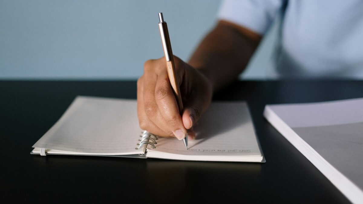 close up shot of a person writing on a notebook