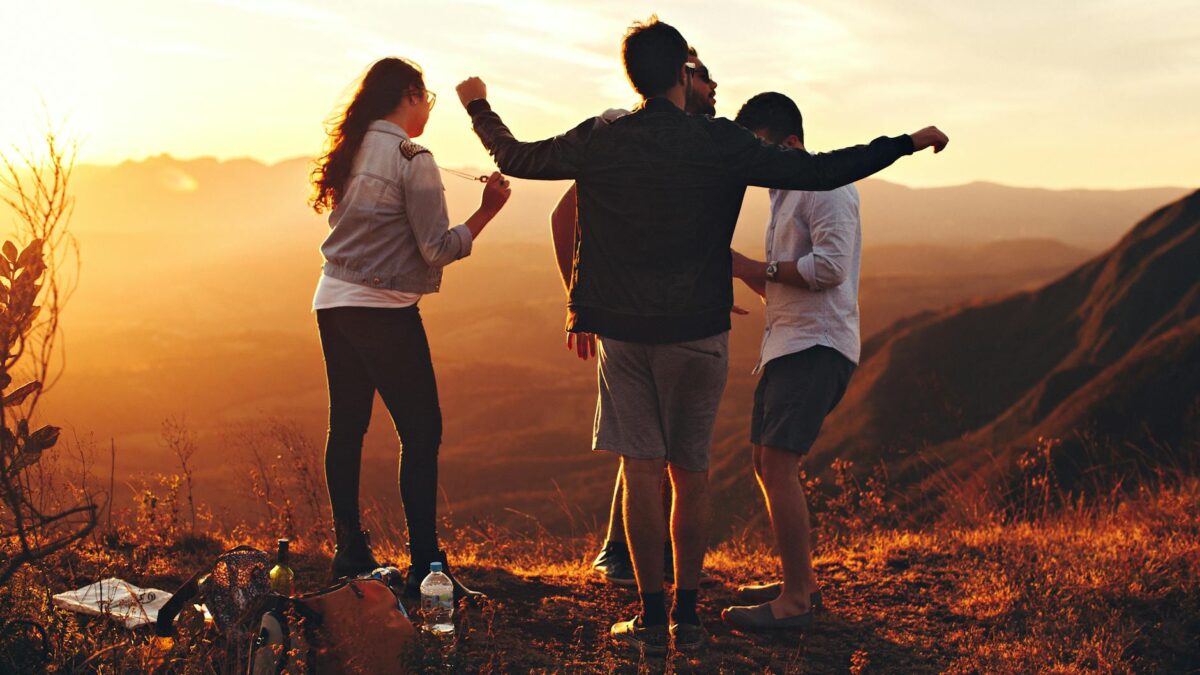 four person standing at top of grassy mountain