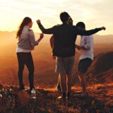 four person standing at top of grassy mountain