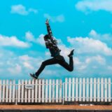 man jumping over white fence