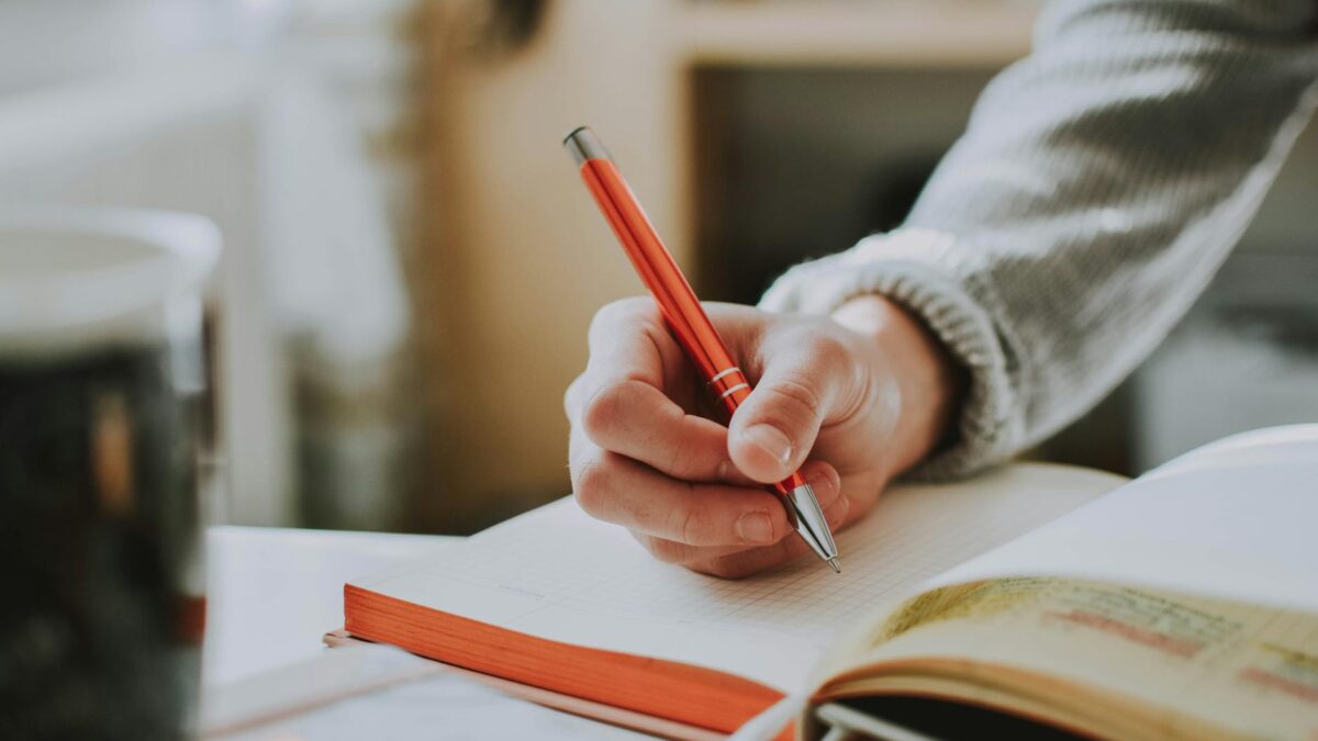 person holding orange pen