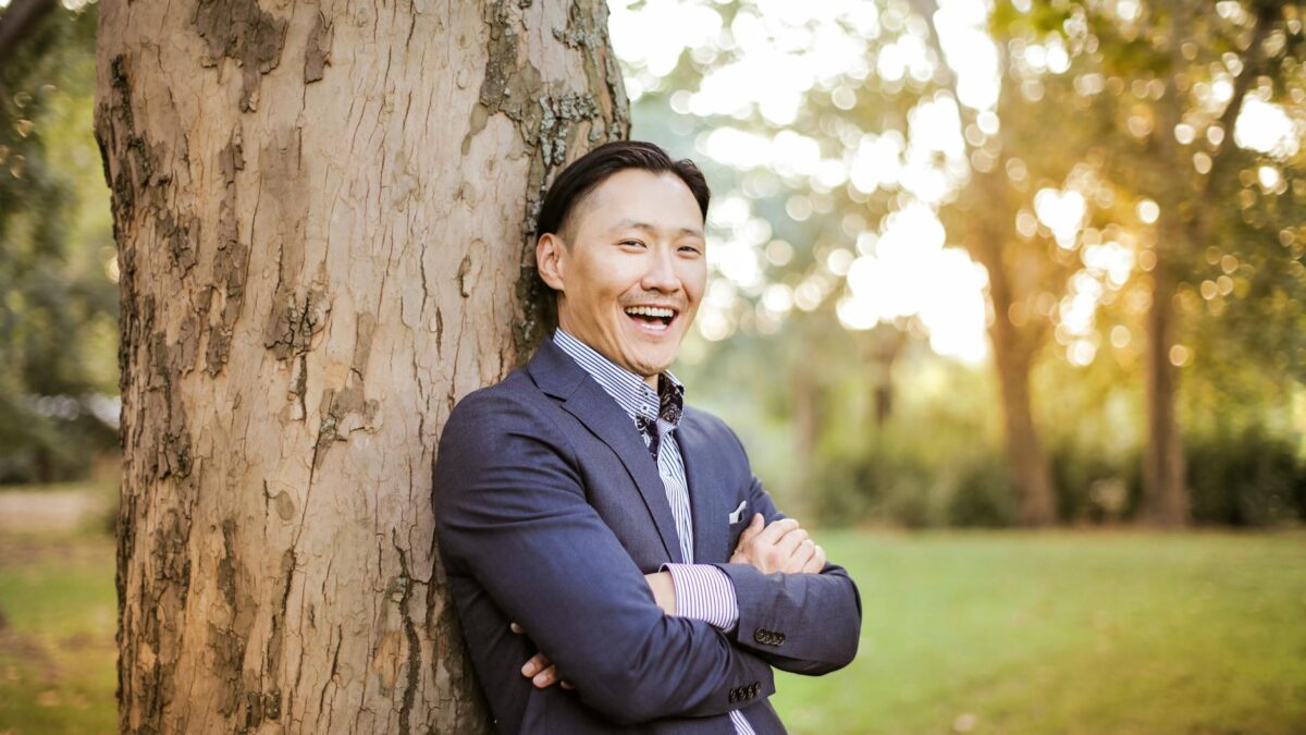 photo of man leaning on tree trunk