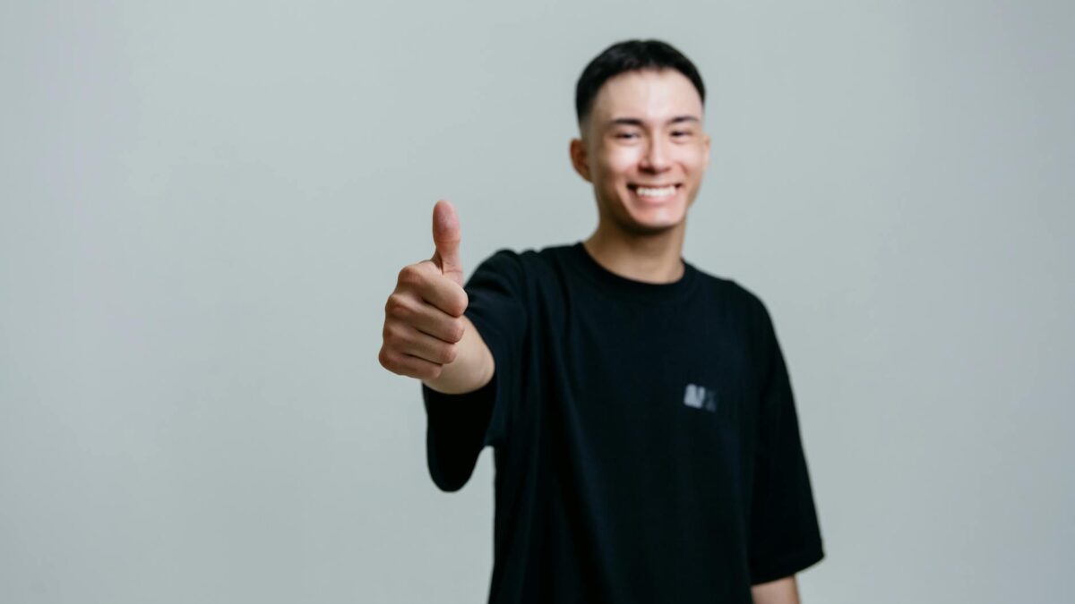 selective focus photo of a man in a black shirt doing the thumbs up