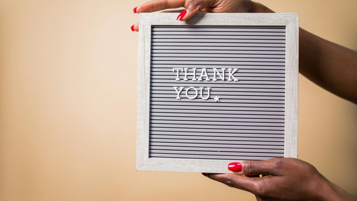 a person holding a gray thank you signage