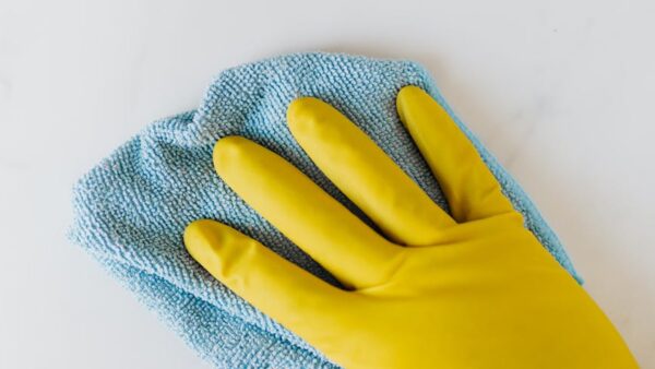 crop unrecognizable person in yellow gloves cleaning white surface