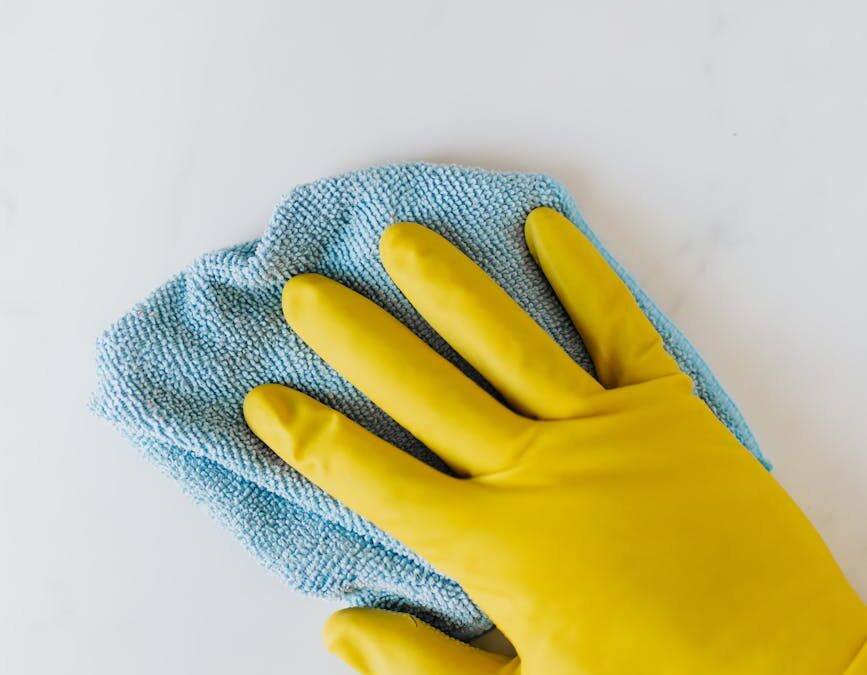crop unrecognizable person in yellow gloves cleaning white surface