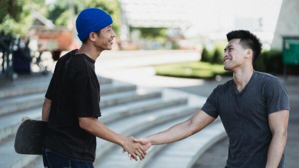 happy asian men shaking hands on sunny street